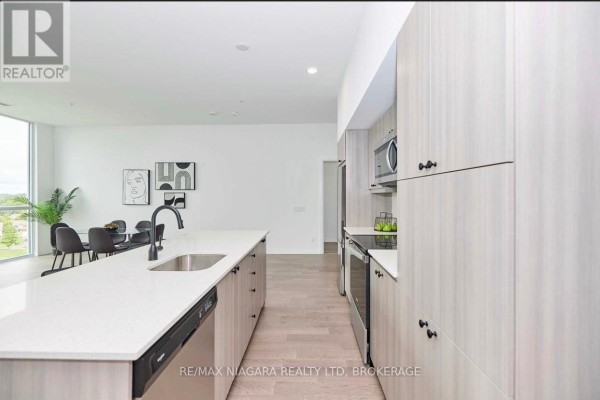Kitchen with island, stainless steel appliances, light wood cabinets, and sink. - Sub_penthouse #914 - 7711 Green Vista Gate, Niagara Falls