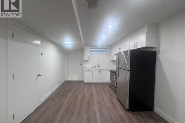 Open concept living area with kitchen and dining space, featuring wood-look flooring and recessed lighting. - Suite 10321 243 St, Maple Ridge