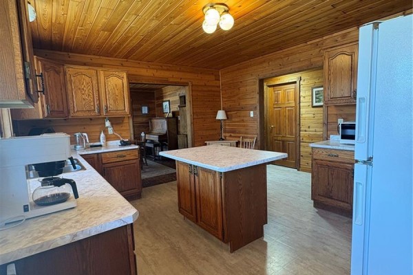 Front of the log house with two large evergreen trees and a sunny sky. - Tatler Horse Acreage, Leask Rm No  464