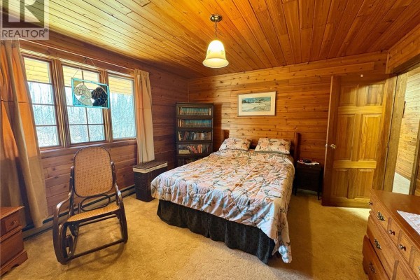 Yard with snow patches, a large evergreen tree, and a view of a wooden fence and flat landscape. - Tatler Horse Acreage, Leask Rm No  464