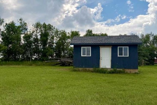 Small, dark blue shed with a white door and two windows, set in a grassy field. - Tbd Namaka Drive, Namaka