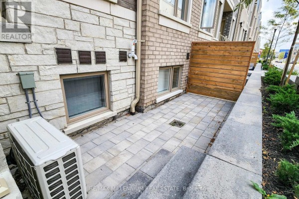 A paved patio area with an outdoor air conditioning unit and wooden privacy screen. - Th 350 - 100 Honeycrisp Crescent, Vaughan
