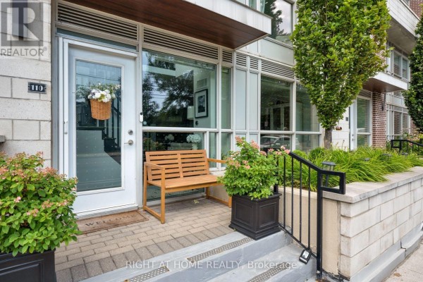 Front entrance of townhouse with glass door, wooden bench, and planters. - Th10 - 1350 Kingston Road, Toronto