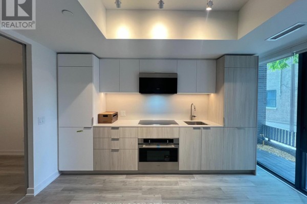 Contemporary kitchen with light wood cabinetry, integrated appliances, and stone countertop. - Th110 - 28 Eastern Avenue, Toronto