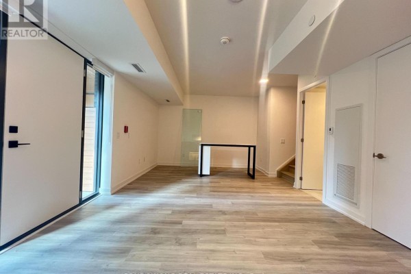 Spacious living area with modern desk, glass partition, and view of stairs. - Th110 - 28 Eastern Avenue, Toronto