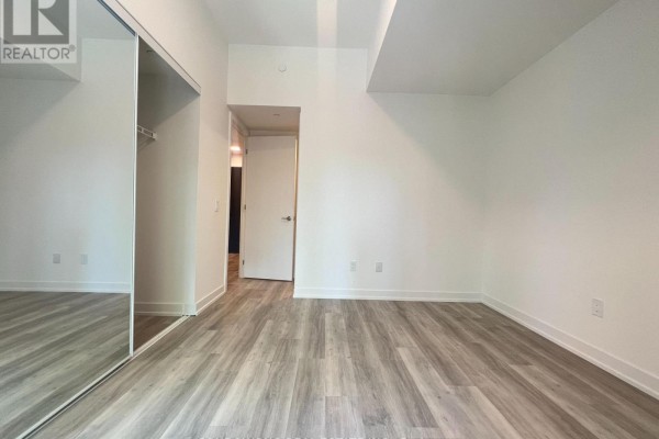Bedroom with mirrored closet doors and view of hallway. - Th110 - 28 Eastern Avenue, Toronto