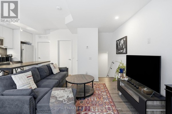 Living room showing a sectional sofa, television, and view of the stairs. - Th12 - 20 Ed Clark Gardens, Toronto