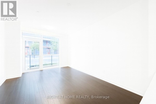 Empty living room with large window, balcony door, dark wood floors, and white walls. - Th15 - 4055 Parkside Drive, Mississauga