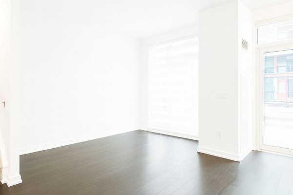 Bright living space with large window, white walls, dark wood floors, and glass door. - Th15 - 4055 Parkside Drive, Mississauga