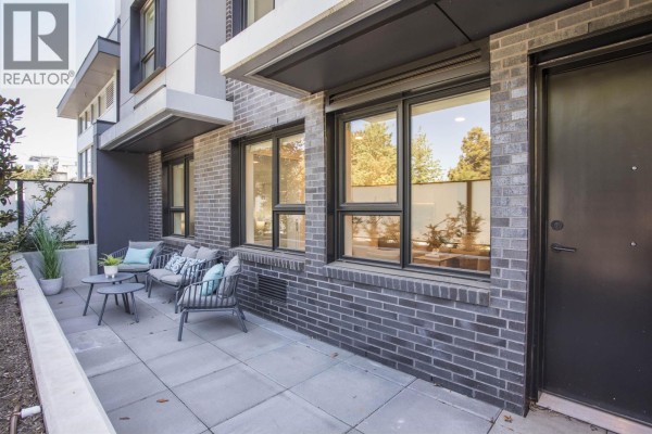 Ground level patio with seating area and dark brick exterior. - Th201 2471 St. George Street, Vancouver