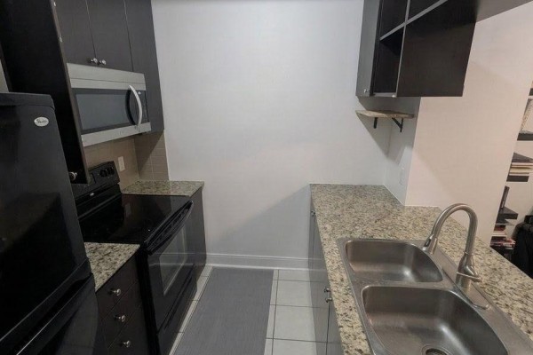 Small kitchen with dark cabinets, granite countertops, stainless steel appliances, and a double sink. - Th25 - 290 Village Green Square, Toronto
