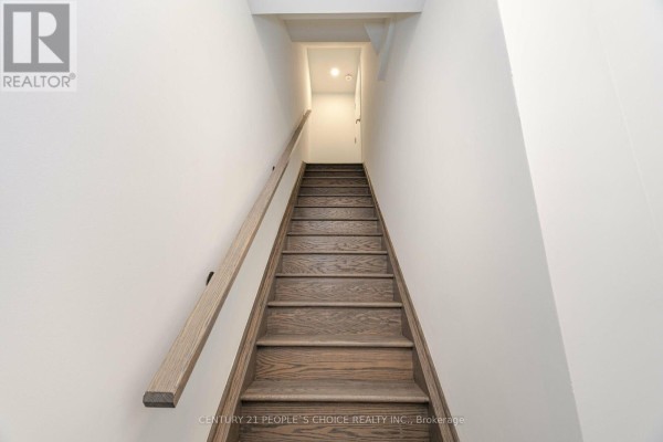 Wooden staircase with a dark wood banister going up against a white wall. - Th263 - 150 Honeycrisp Crescent N, Vaughan
