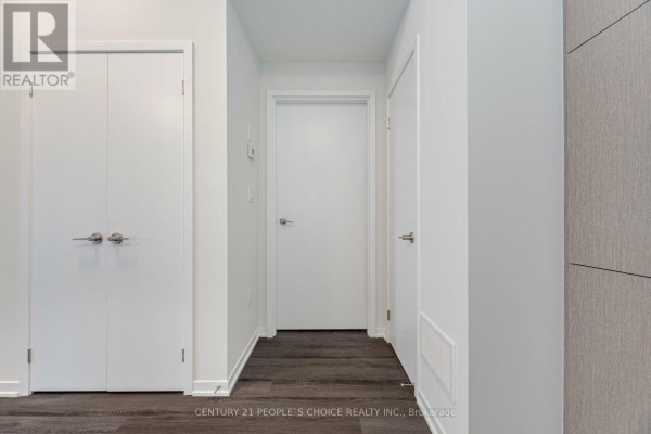 Interior hallway with white doors, one double closet, and dark wood-look flooring. - Th263 - 150 Honeycrisp Crescent N, Vaughan