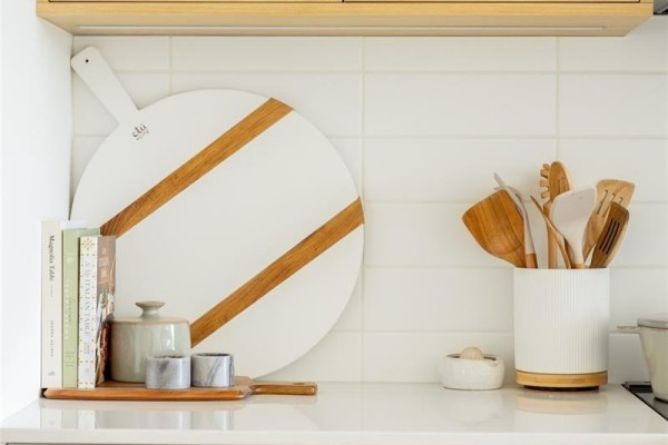 Close-up of kitchen backsplash with white subway tile, round cutting board, and kitchen utensils. - Th6 3450 Whittier Ave, Saanich