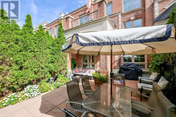 Patio with outdoor dining set, BBQ, and green foliage. - Th9 - 21 Burkebrook Place, Toronto