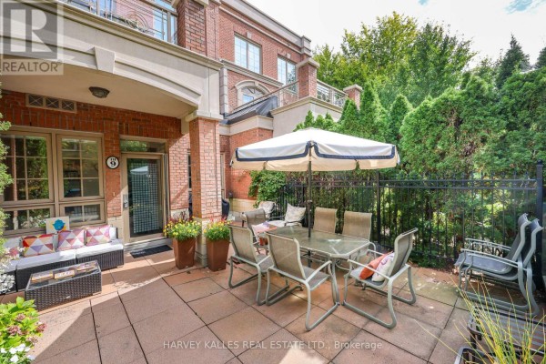 Paved patio with outdoor seating, dining table, and umbrella. - Th9 - 21 Burkebrook Place, Toronto