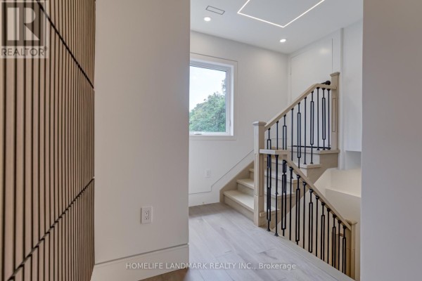 Interior staircase with light wood floors, white walls, and a decorative wood wall panel. - The Palazzo - 23 Coulson Avenue, Toronto