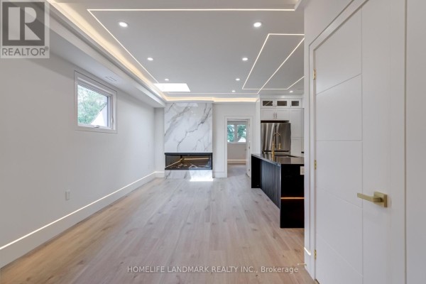 Living area with a marble fireplace, recessed lighting, and an open concept kitchen. - The Palazzo - 23 Coulson Avenue, Toronto