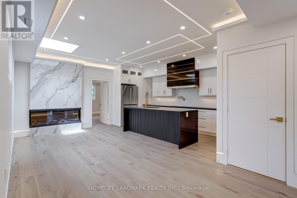Spacious open-concept living and kitchen area with a large island and modern fireplace. - The Palazzo - 23 Coulson Avenue, Toronto
