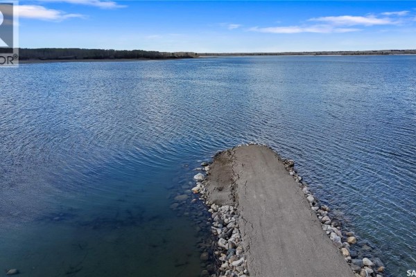 Paved road with stone embankment leading into Iroquois Lake. - The Woodlands, Iroquois Lake