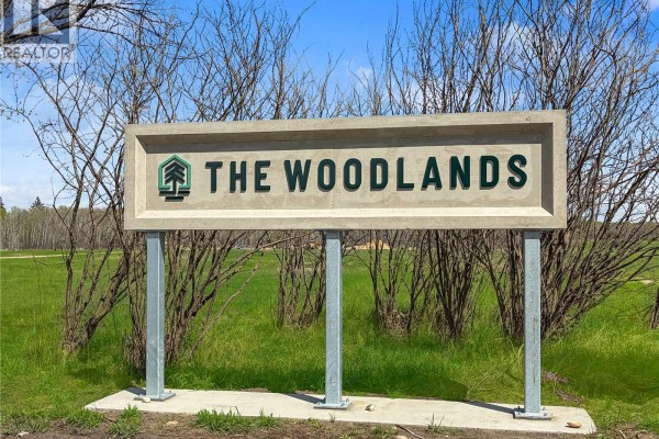 Concrete monument sign for "THE WOODLANDS" development with green lettering. - The Woodlands, Iroquois Lake