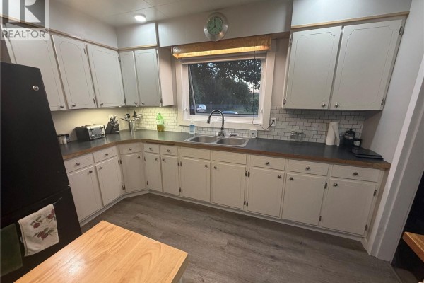 Kitchen featuring white cabinets, dark counters, a stainless steel refrigerator, and a window. - Thiessen Acreage, Laird Rm No  404