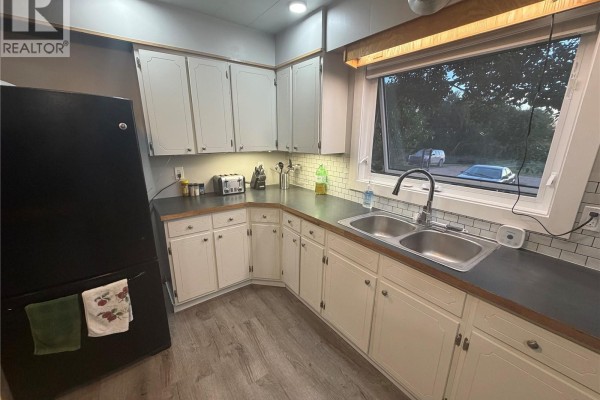 Kitchen with a central island, stainless steel appliances, and white cabinets and backsplash. - Thiessen Acreage, Laird Rm No  404