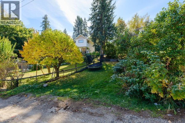 A wide shot of a residential property with trees and a white house. - Third Avenue Lot# Lot 7, Rossland