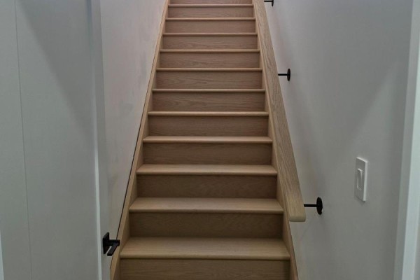 Wooden staircase with light wood treads and railing against a white wall. - Third Floor - 701 Queen Street W, Toronto