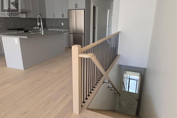 View from a landing looking down a tiled staircase, with a modern kitchen above. - Third Floor - 701 Queen Street W, Toronto