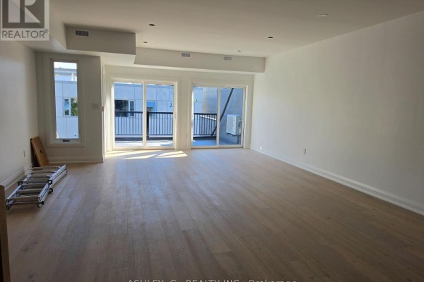 Bright, open living space with light wood floors and glass sliding doors to a balcony. - Third Floor - 701 Queen Street W, Toronto