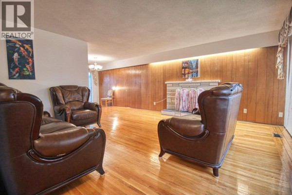 Living room with leather seating, fireplace, and wood-paneled accent wall. - Top 904 E 52nd Avenue, Vancouver