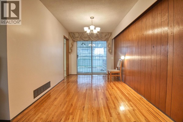 Dining area with wood-paneled wall, chandelier, and sliding glass door. - Top 904 E 52nd Avenue, Vancouver