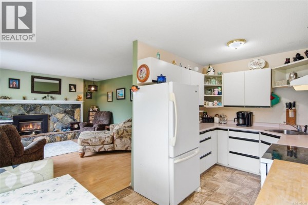 View from living room into a kitchen with white cabinets, a white refrigerator, and stainless steel appliances. - Trunk Rd 7 Trunk Rd, Duncan