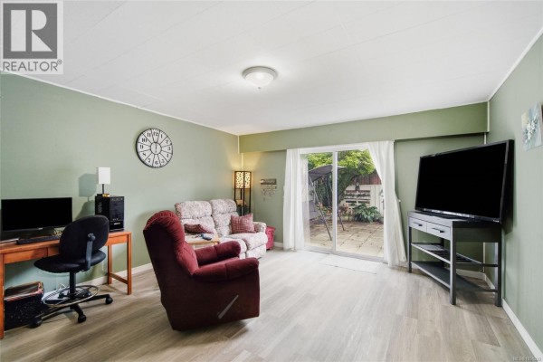 Family room with a desk, sofa, recliner, and sliding glass doors opening to an outdoor patio. - Trunk Rd 7 Trunk Rd, Duncan