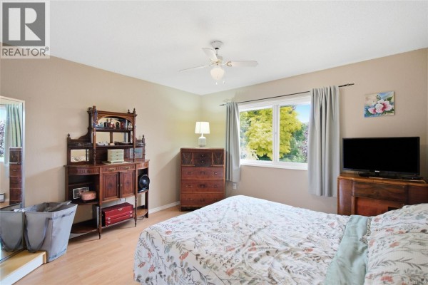 Bedroom with a queen-size bed, dresser, and window overlooking trees and foliage. - Trunk Rd 7 Trunk Rd, Duncan