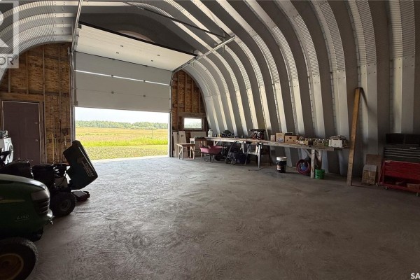 Interior of a quonset hut garage with a large open door and farming equipment. - Turtleford Acreage., Mervin Rm No 499
