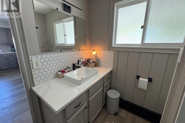Bathroom vanity with a vessel sink, white hexagonal backsplash, and a large mirror. - Unit 1 - 1022 Ridge Road, Fort Erie