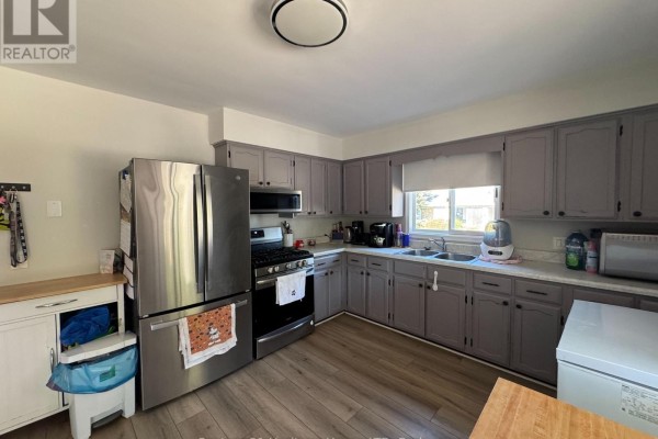 Kitchen with grey cabinets, stainless steel refrigerator, gas stove, and wood-look flooring. - Unit 1 - 1022 Ridge Road, Fort Erie