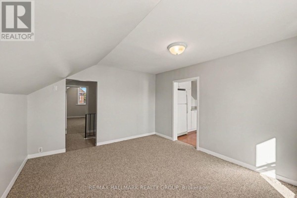 Interior view of a carpeted room showing two doorways, one leading to a kitchen area. - Unit 1 - 216 Bell Street, Arnprior