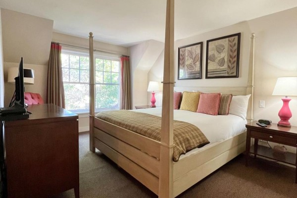 A bright bedroom with a king-size four-poster bed, pink lamps, and framed botanical art. - Unit 11 - 301 Emerald Hills Court, Seguin