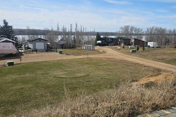A recreational vehicle parked next to a wooden deck with a covered roof. - Unit 118, 65275 Range Road 114a, Lac La Biche