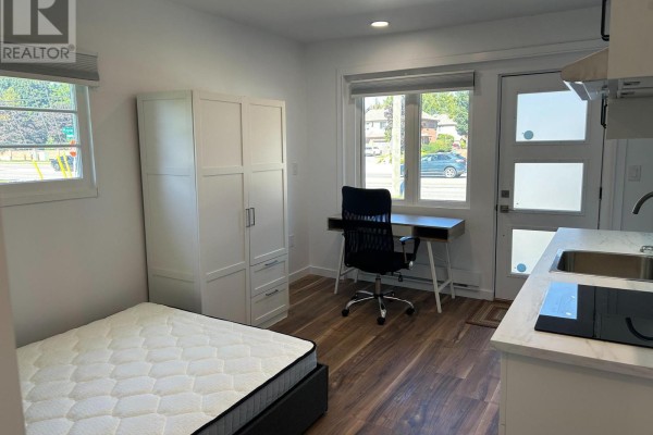 Studio interior showing a mattress, white wardrobe, desk with black chair, and a small kitchenette counter. - Unit 2 - 1473 Adelaide Street N, London North