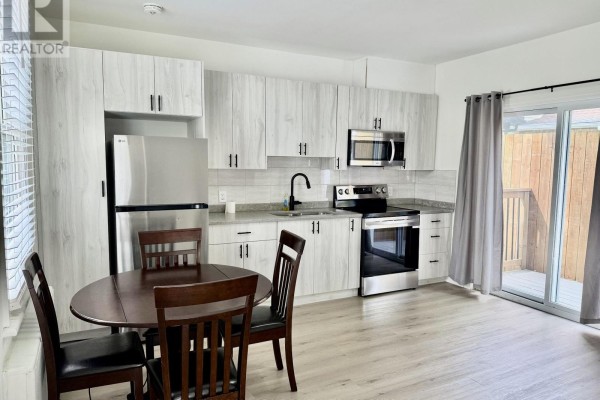 Back deck with wood railing and composite decking, accessed through a sliding glass door. - Unit 2 - 4711 River Road, Niagara Falls