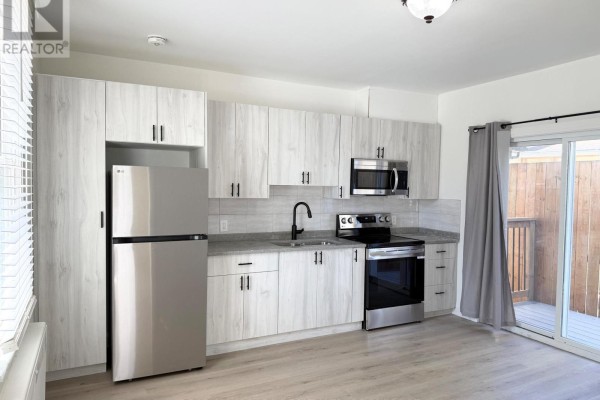 Open concept living and kitchen area with light laminate flooring and white walls. - Unit 2 - 4711 River Road, Niagara Falls