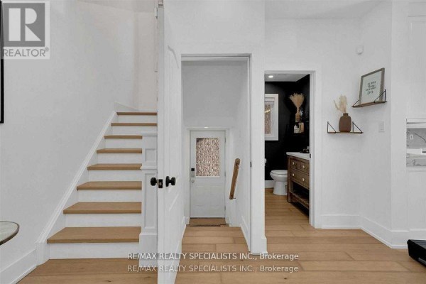 Hallway with white walls, wood floor, and light wood staircase. - Unit 2 - 7294 Rosehurst Drive, Mississauga