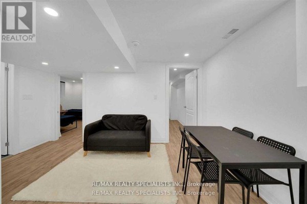 Basement living area with a dark sofa, dining table, and chairs. - Unit 2 - 7294 Rosehurst Drive, Mississauga