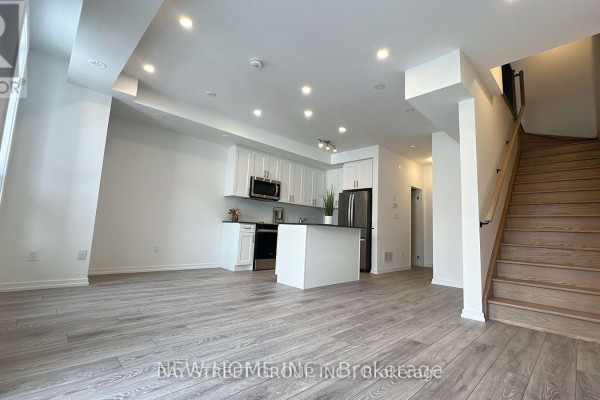 Open concept living area with kitchen and stairs leading up. - Unit 20-24 Lytham Green Circle, Newmarket