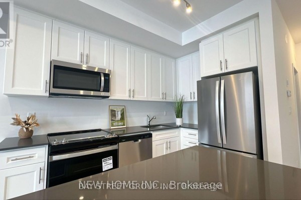 Close-up of kitchen with white cabinetry and stainless steel refrigerator. - Unit 20-24 Lytham Green Circle, Newmarket
