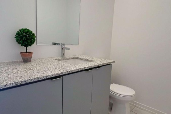 Bathroom vanity with granite countertop, stainless steel faucet, and toilet. - Unit 20-24 Lytham Green Circle, Newmarket